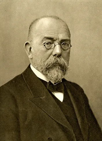 Studio portrait of Robert Koch, a bearded man wearing round spectacles and a dark suit.